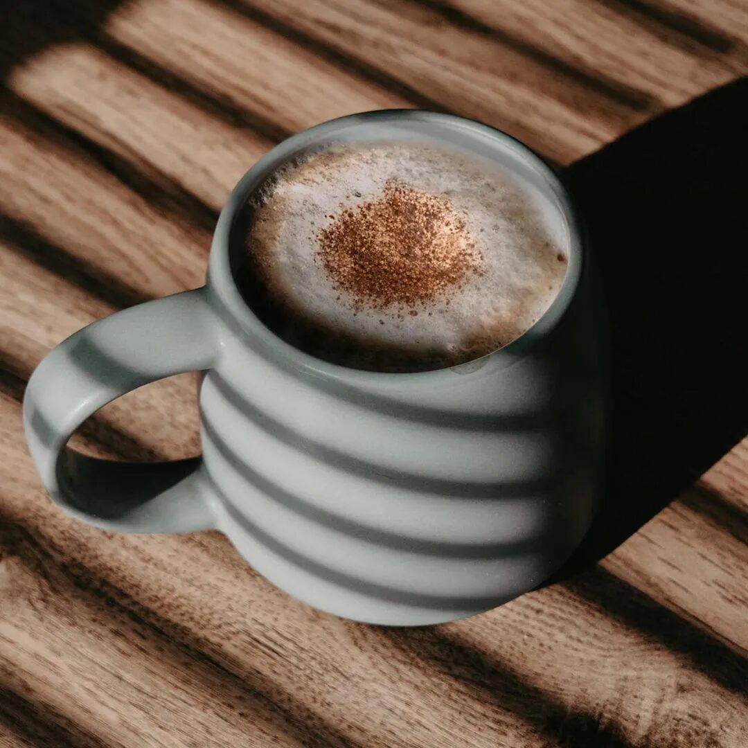 Latte with cinnamon in a striped ceramic mug